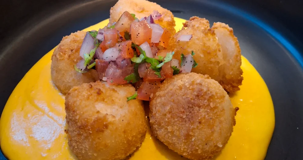 Chabuca’s Yuquitas Inka: crispy cheese-filled yuca balls topped with bright chalaquita over a pool of Huancaina sauce.topped with bright chalaquita over a pool of huancaina sauce.