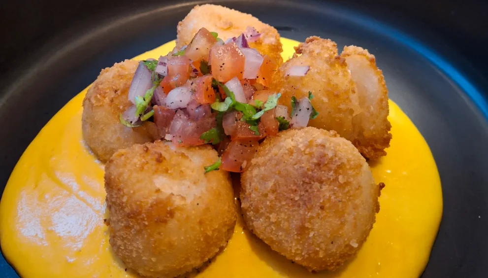 Chabuca’s Yuquitas Inka: crispy cheese-filled yuca balls topped with bright chalaquita over a pool of Huancaina sauce.topped with bright chalaquita over a pool of huancaina sauce.