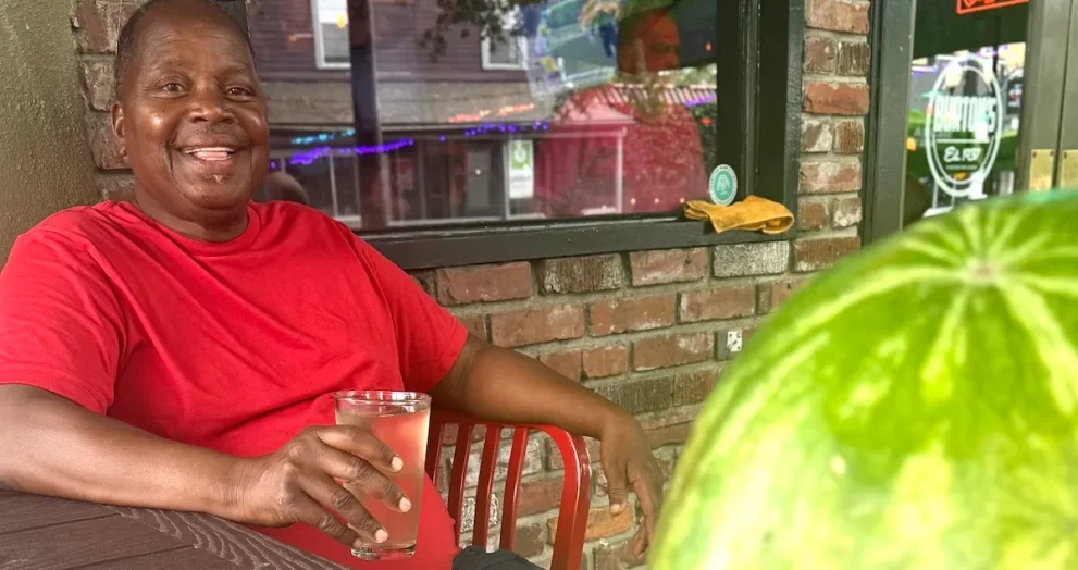 Michael Sears, a Gifford artist and Highwaymen tradition painter, photographed at Burton’s in Orlando with a watermelon and a poster for his documentary La Dolce Prospettiva.