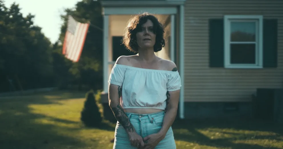 Lilly Hiatt standing in front of a house with an American flag in the background.