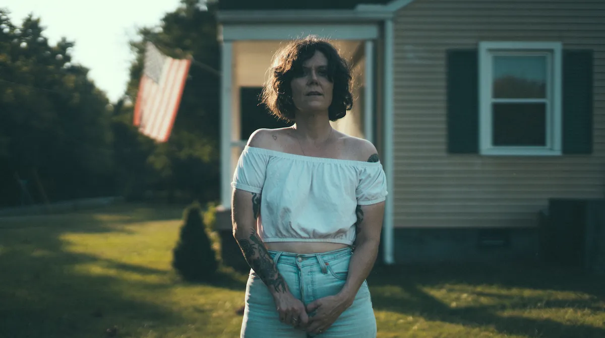 Lilly Hiatt standing in front of a house with an American flag in the background.