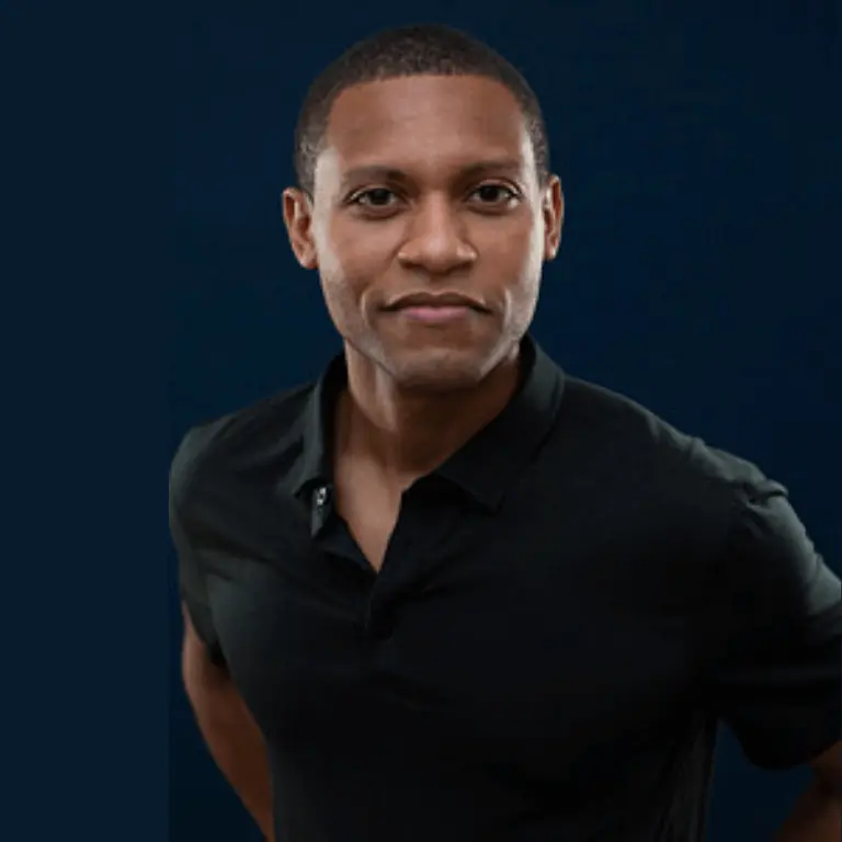 Studio portrait of Brandon Martin, a person in a black collared shirt against a dark blue background, facing forward with a relaxed posture.