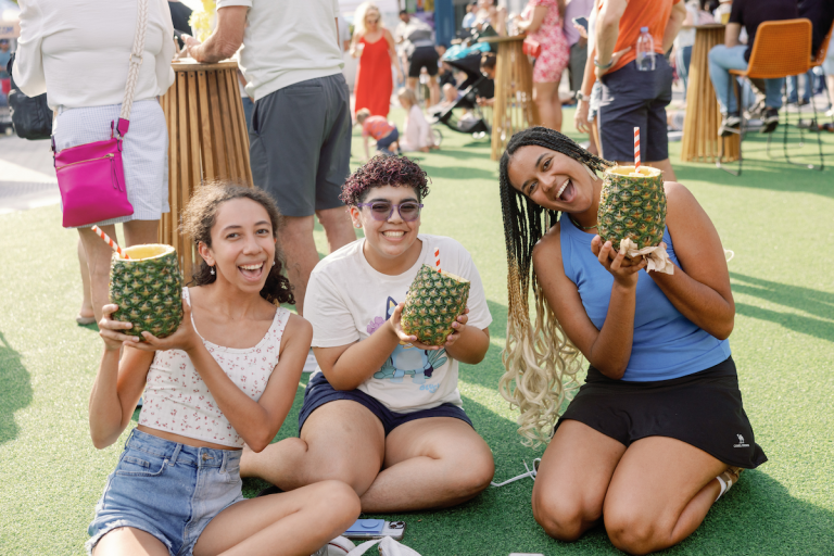 Three people enjoy pineapple drinks while sitting outside at Lake Nona Pineapple Festival
