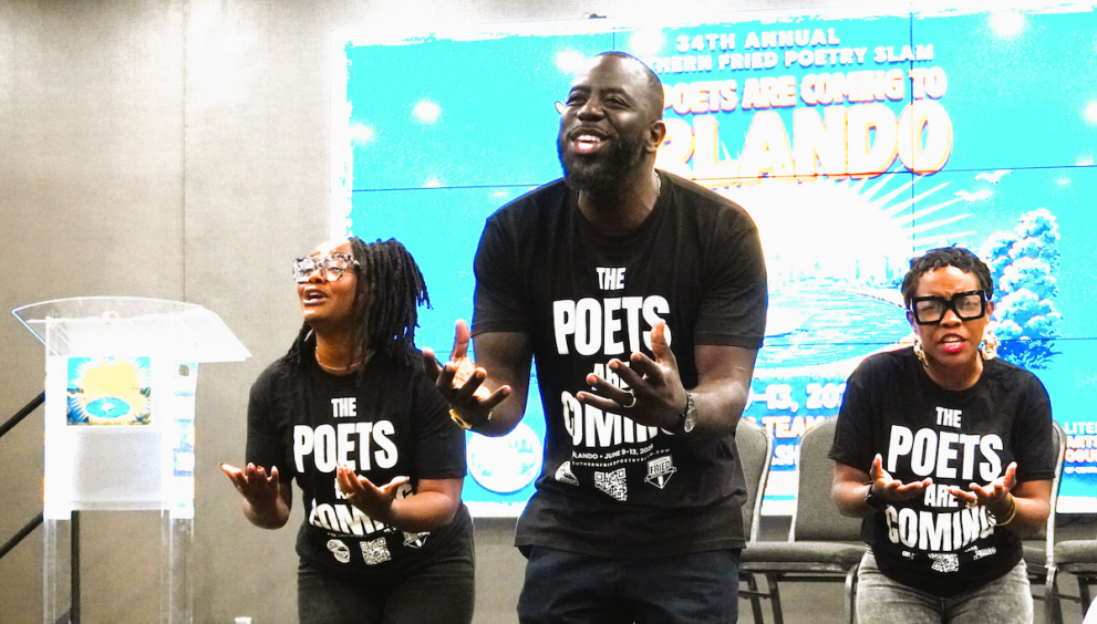 Three poets wearing matching black t-shirts that read "The Poets Are Coming" perform with expressive hand gestures on a stage in Orlando, Florida.