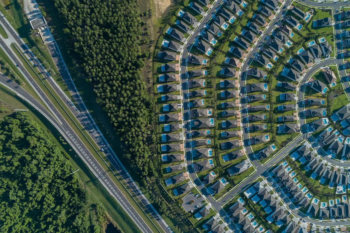 Carlton Ward Jr. photo titled Encroachment shows a housing development bordering the city of Orlando. Rows of housing spread outward in a half an octagon, replacing acres of forest and butting up to a highway.