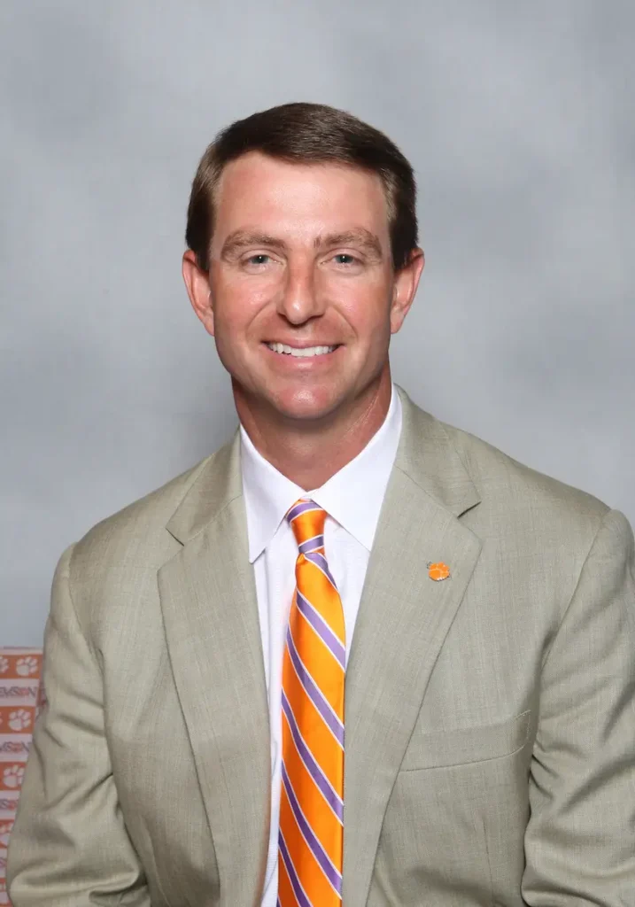 Dabo Swinney, Clemson college football coach, wearing a beige jacket and orange tie for official coaching staff photo