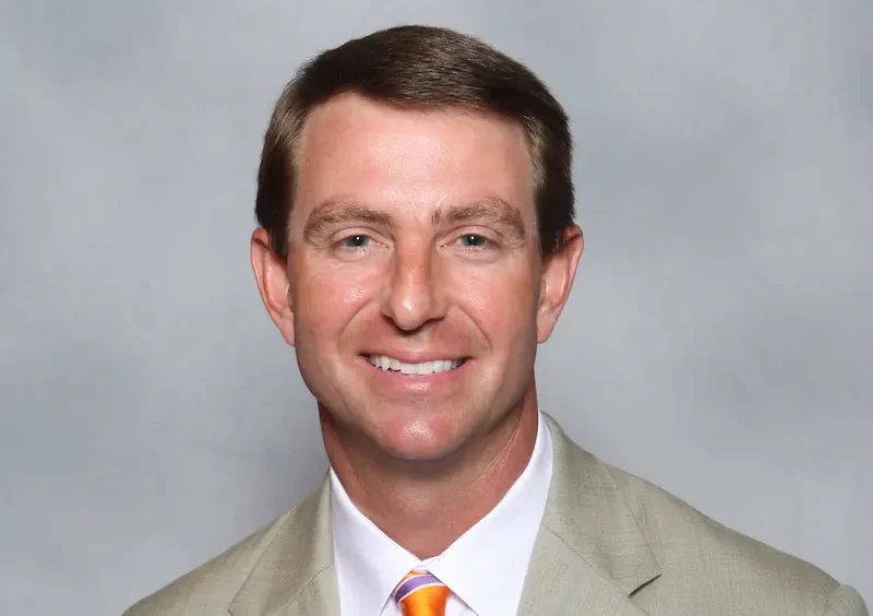 Dabo Swinney, Clemson college football coach, wearing a beige jacket and orange tie for official coaching staff photo