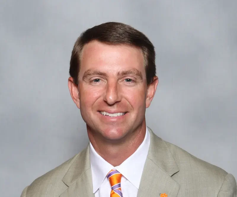 Dabo Swinney, Clemson college football coach, wearing a beige jacket and orange tie for official coaching staff photo